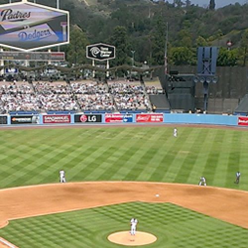 A view of a baseball game in progress at Dodger Stadium with fans in attendance, players on the field, and various advertisements visible.