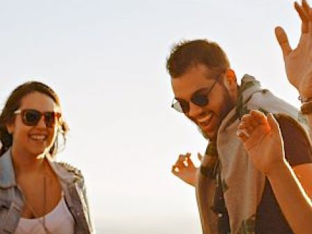 A group of people outdoors, smiling, and enjoying a sunny day; they appear to be having a good time together.